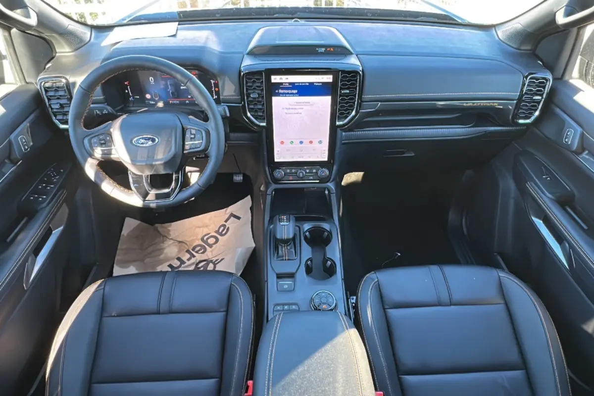 Vue intérieure du Ford Ranger 2025 Wildtrak Plus montrant le tableau de bord noir avec écran tactile vertical et volant multifonctions.