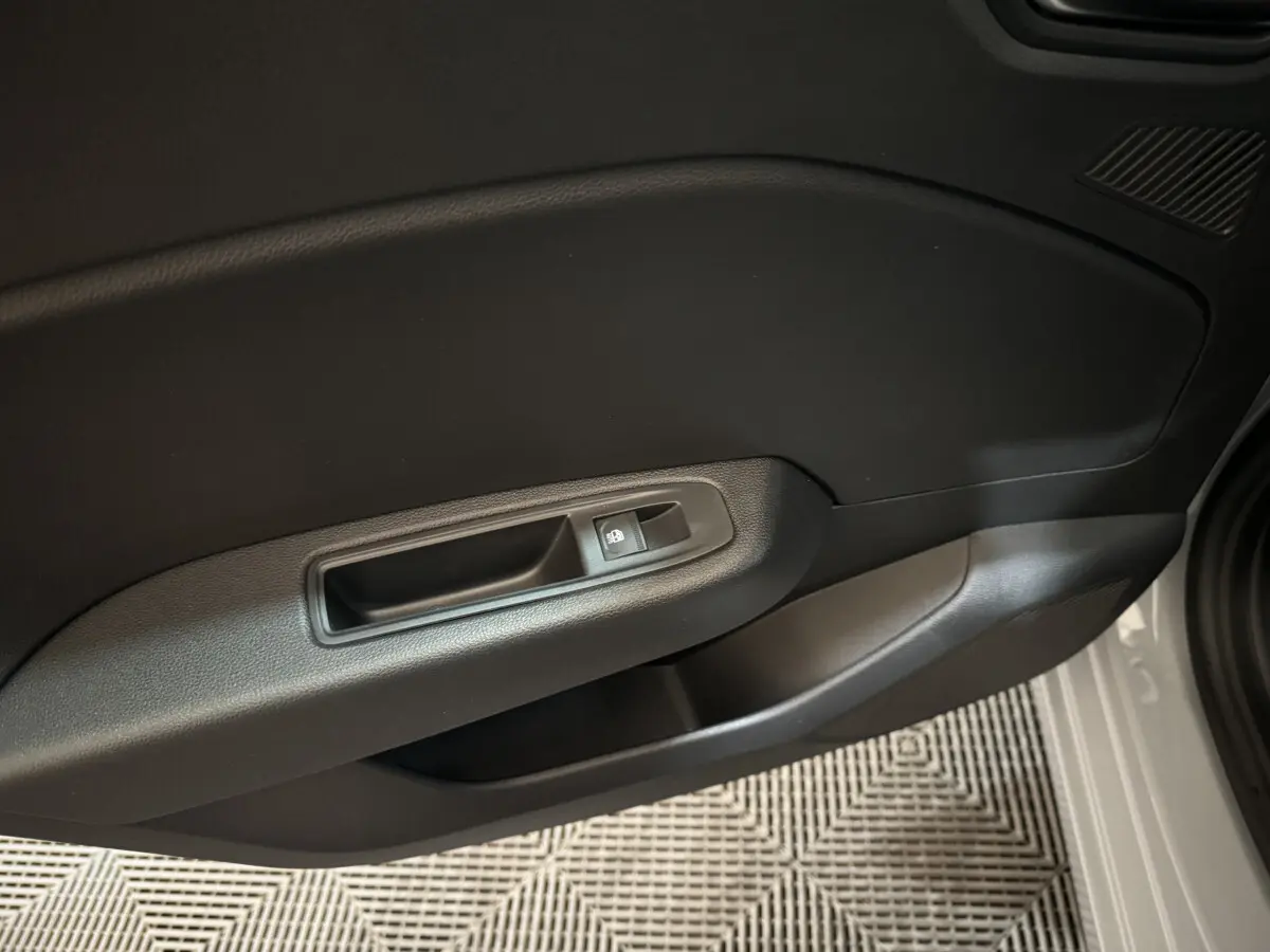 Vue rapprochée de la porte côté droit de la Renault Clio gris clair, avec poignée intérieure et bouton de verrouillage.