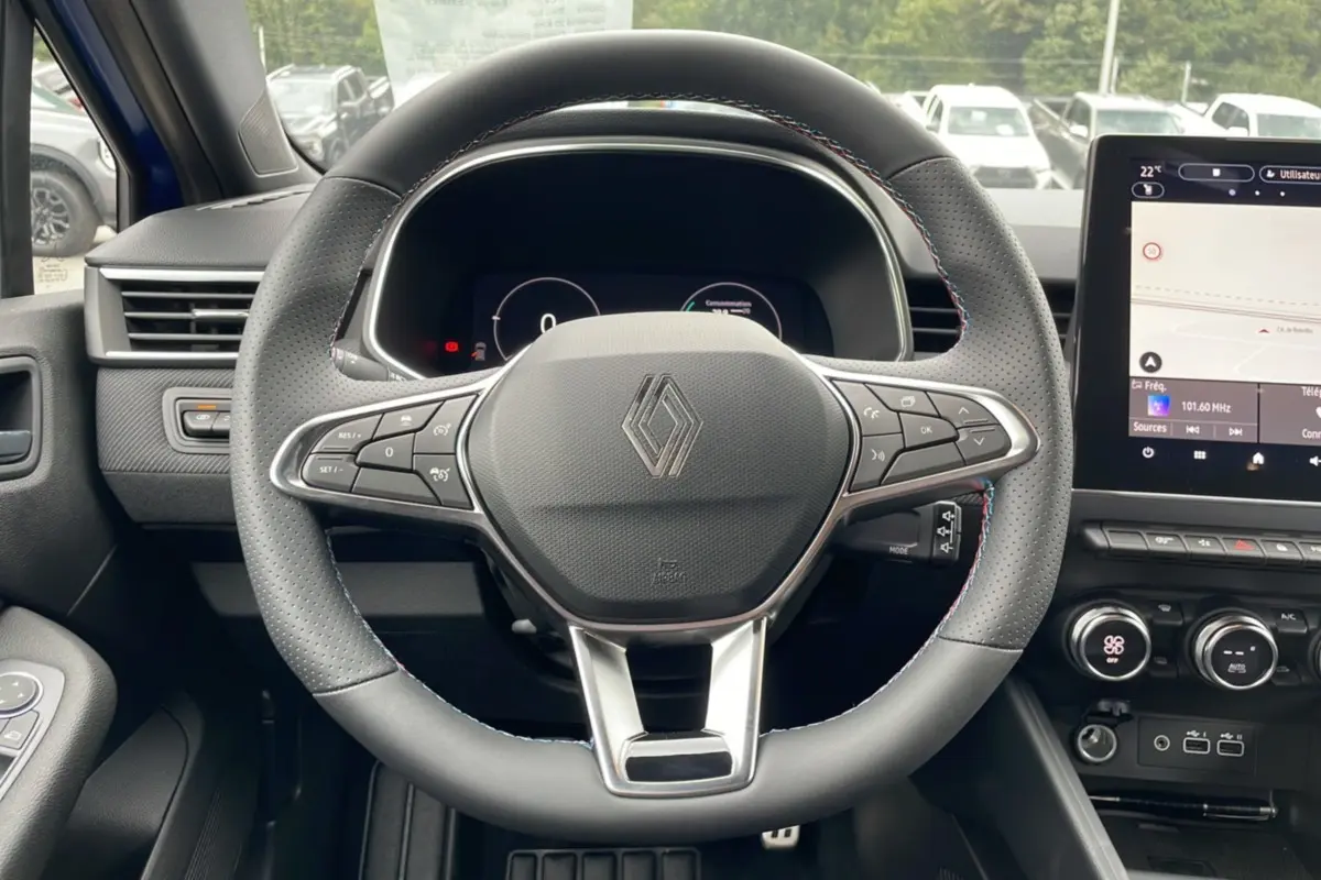 Vue centrée du volant perforé de la Renault Clio V TCE 90 Esprit Alpine 2025 avec tableau de bord numérique et écran tactile.