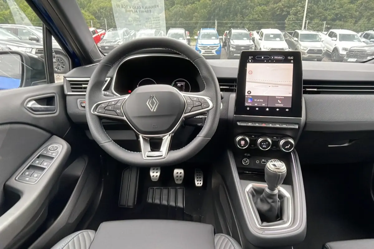 Intérieur de la Renault Clio V TCE 90 Esprit Alpine 2025 en bleu iron, vue frontale sur le volant, tableau de bord et levier manuel.