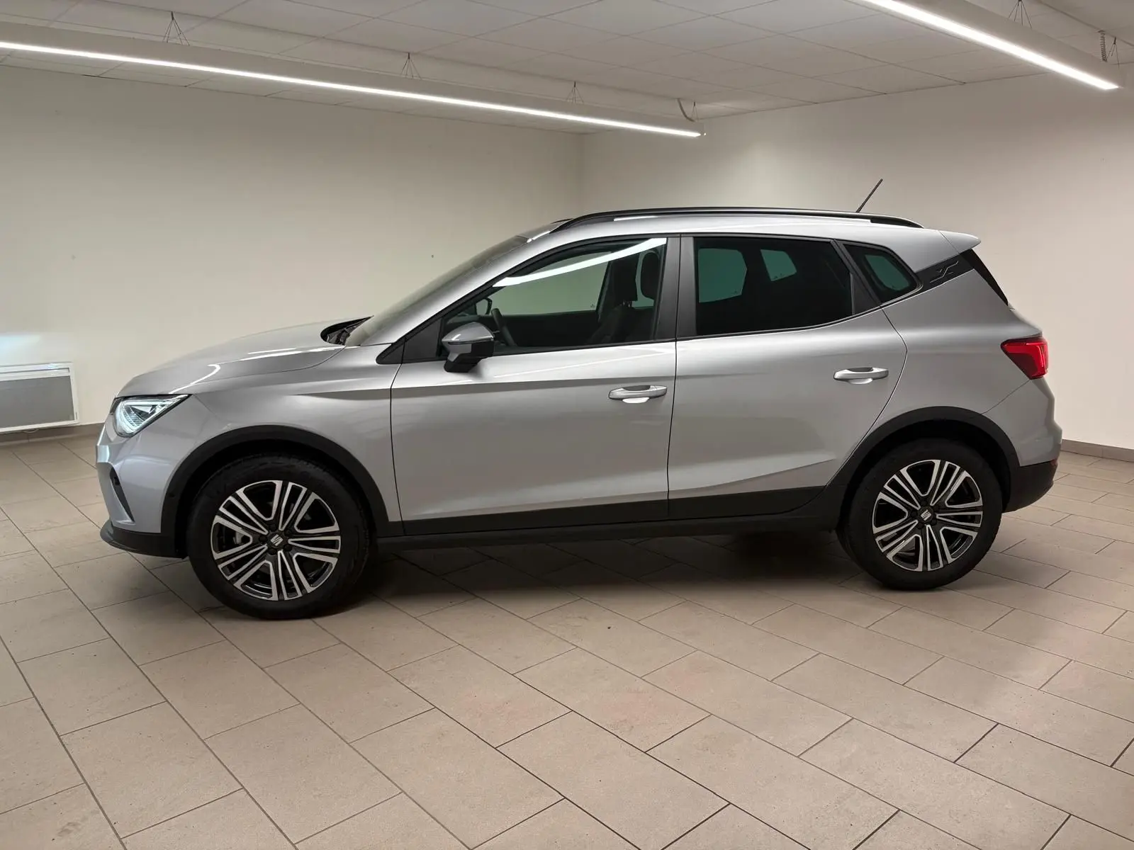 SEAT Arona 2024 gris urbain en vue profil côté gauche, avec vitres arrière surteintées et jantes alliage.