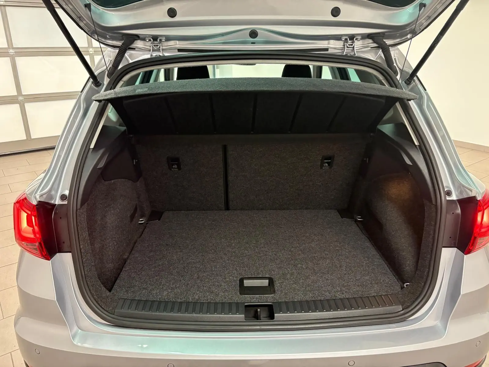 Coffre ouvert vu de l'arrière d'un SEAT Arona 2024 gris urbain avec vitres surteintées arrière.