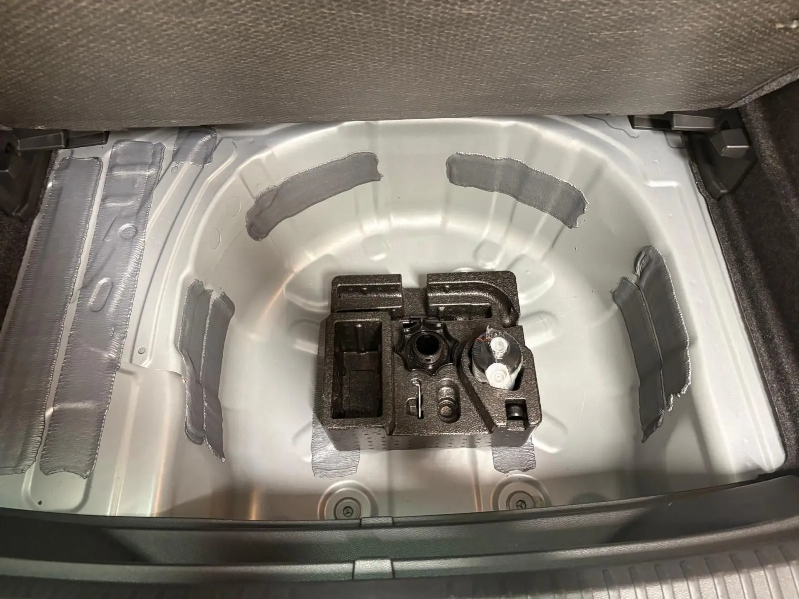 Coffre ouvert du SEAT Arona 2024 montrant la roue de secours et le rangement intérieur gris métallique.