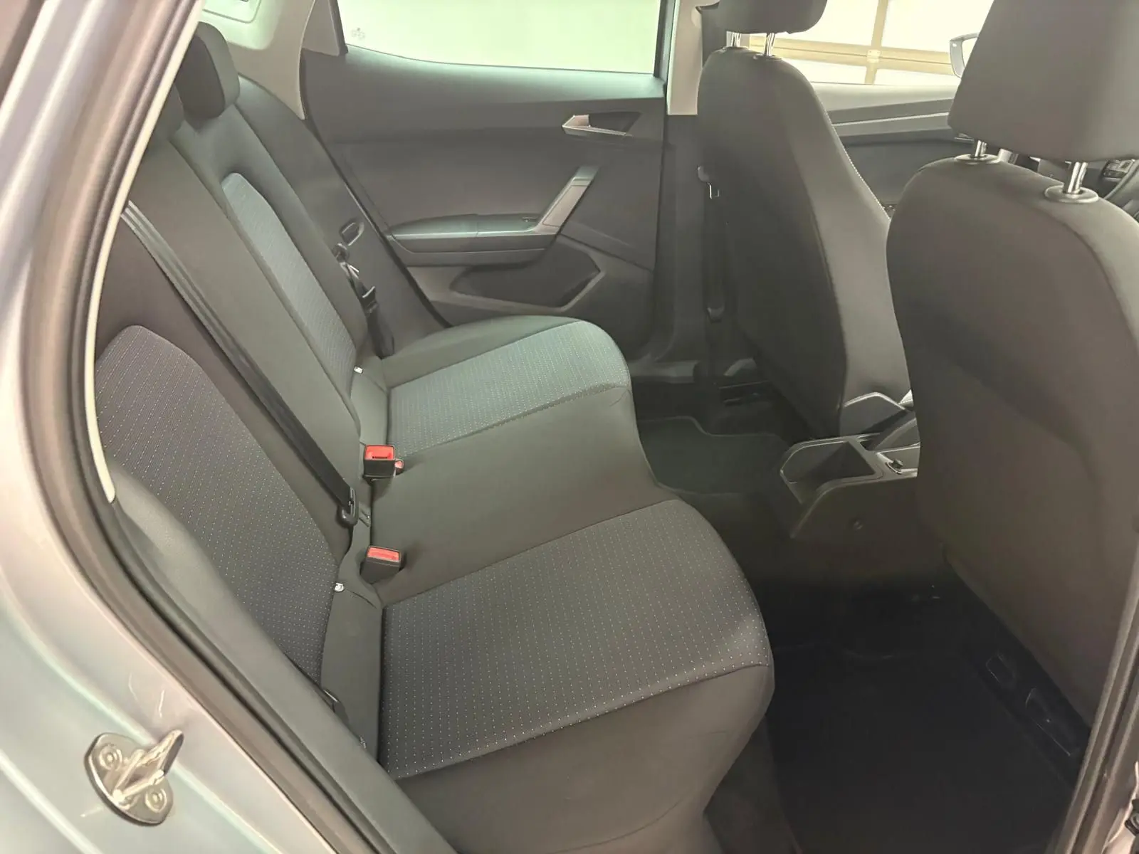 Vue intérieure arrière gauche des sièges tissu gris du SEAT Arona 2024 avec portières ouvertes et vitres surteintées.