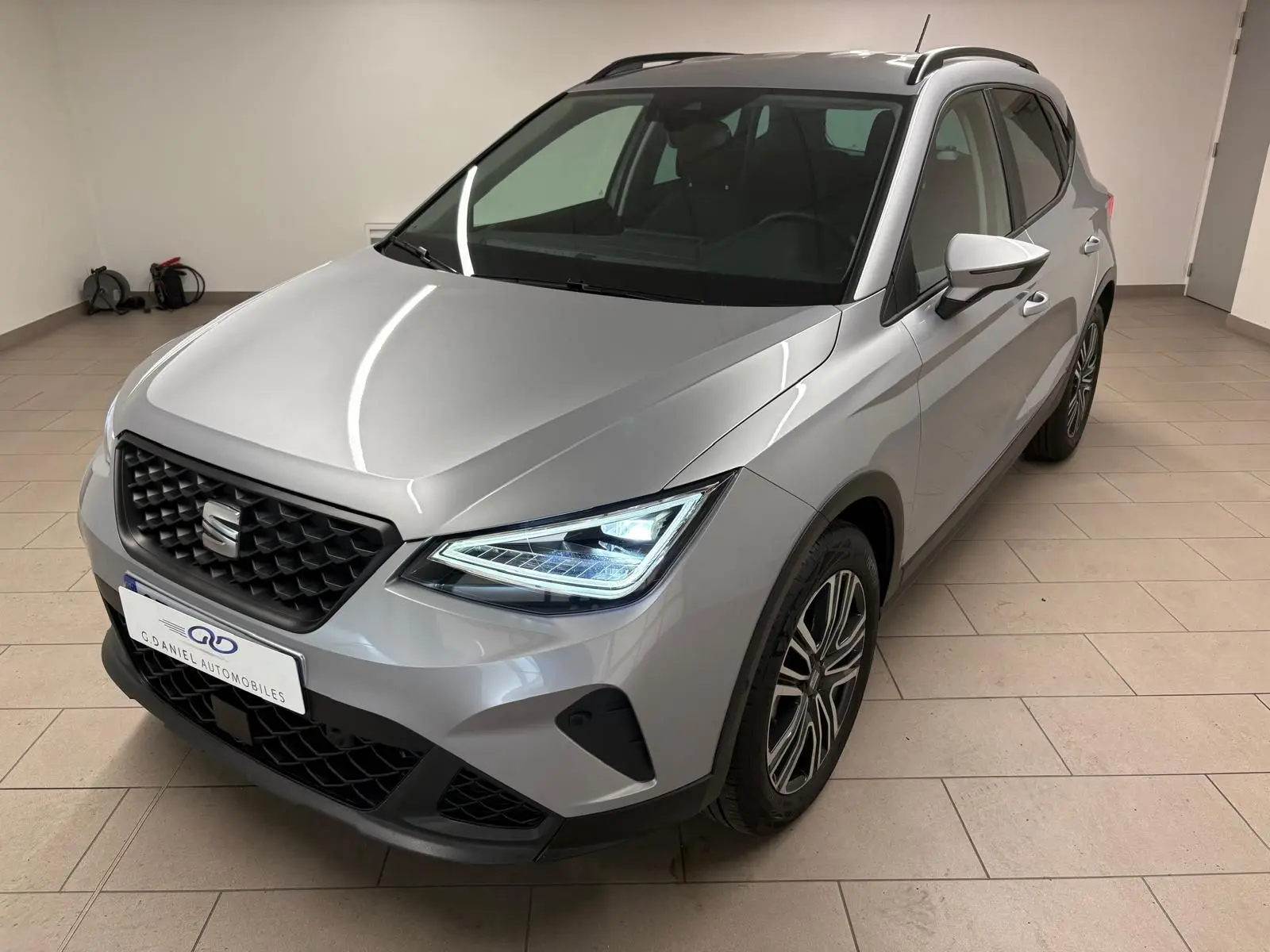 SEAT Arona 2024 gris urbain en 3/4 avant droit avec phares LED et vitres arrière surteintées.