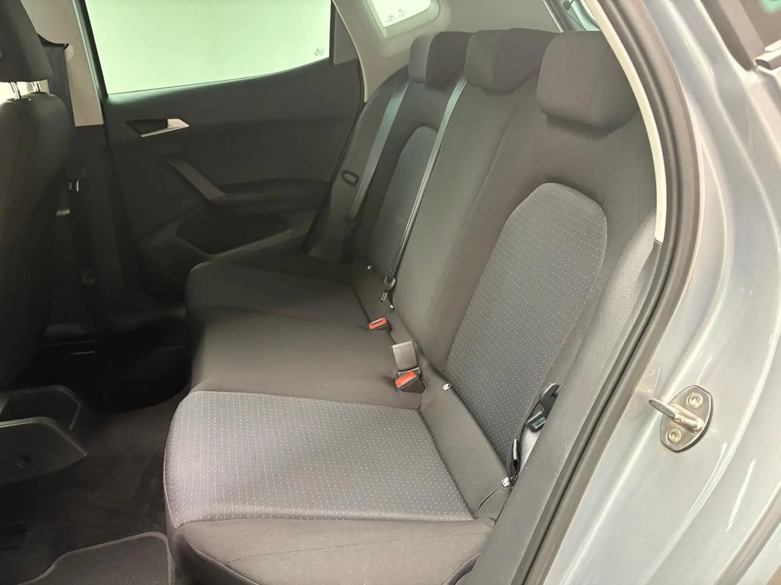Vue latérale des sièges arrière en tissu gris foncé du SEAT Arona 2024 avec portière ouverte côté droit.