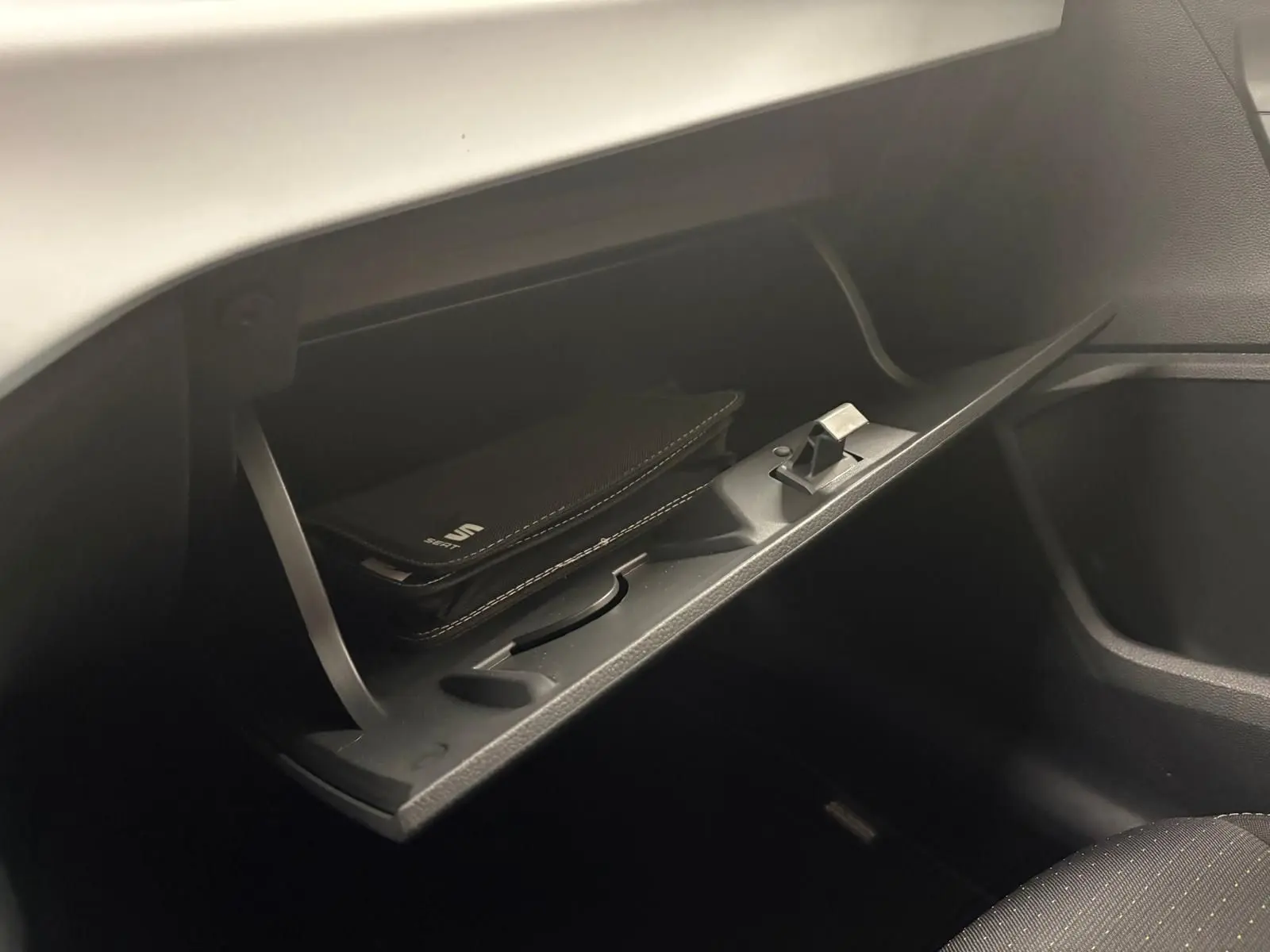 Gros plan sur la boîte à gants ouverte du SEAT Arona 2024, avec un étui noir marqué SEAT à l'intérieur.