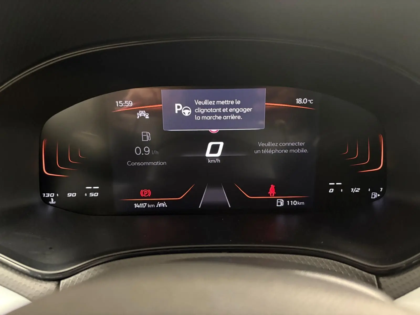 Tableau de bord numérique du SEAT Arona 2024 affichant la consommation, la vitesse à 0 km/h et un message d'alerte.