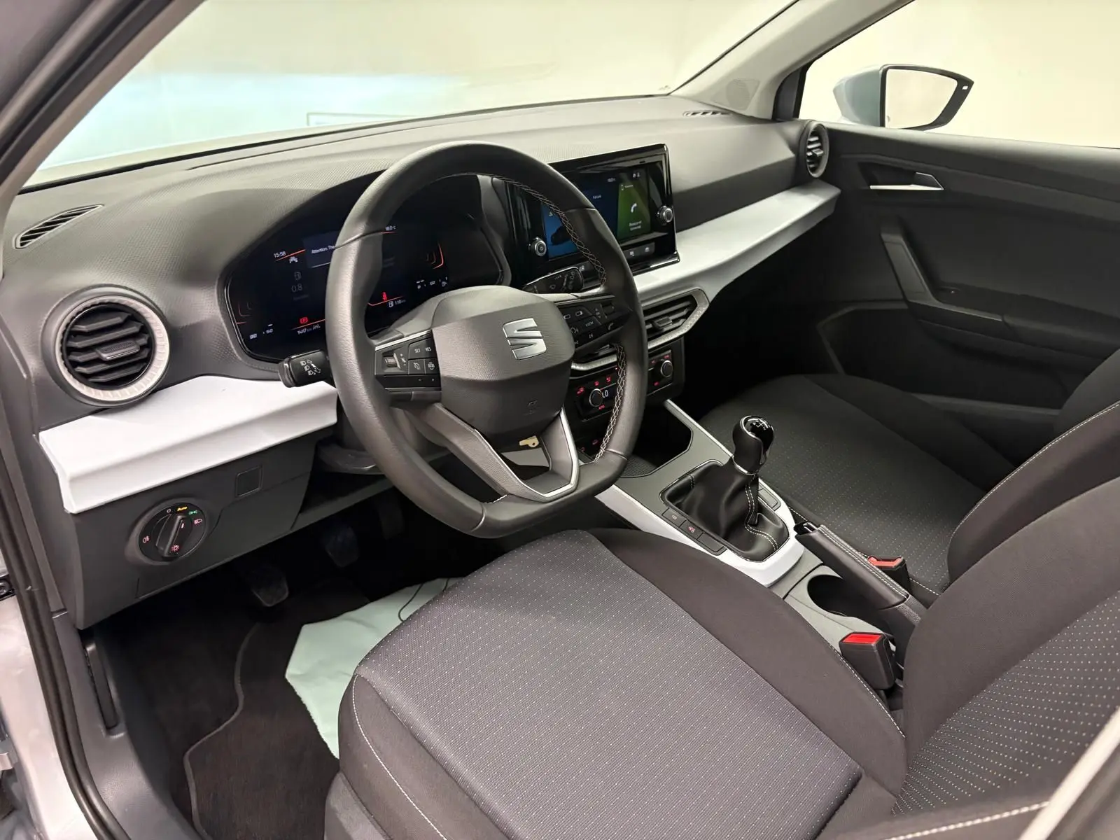 Intérieur avant droit du SEAT Arona 2024 avec volant multifonction, tableau de bord numérique et boîte manuelle.
