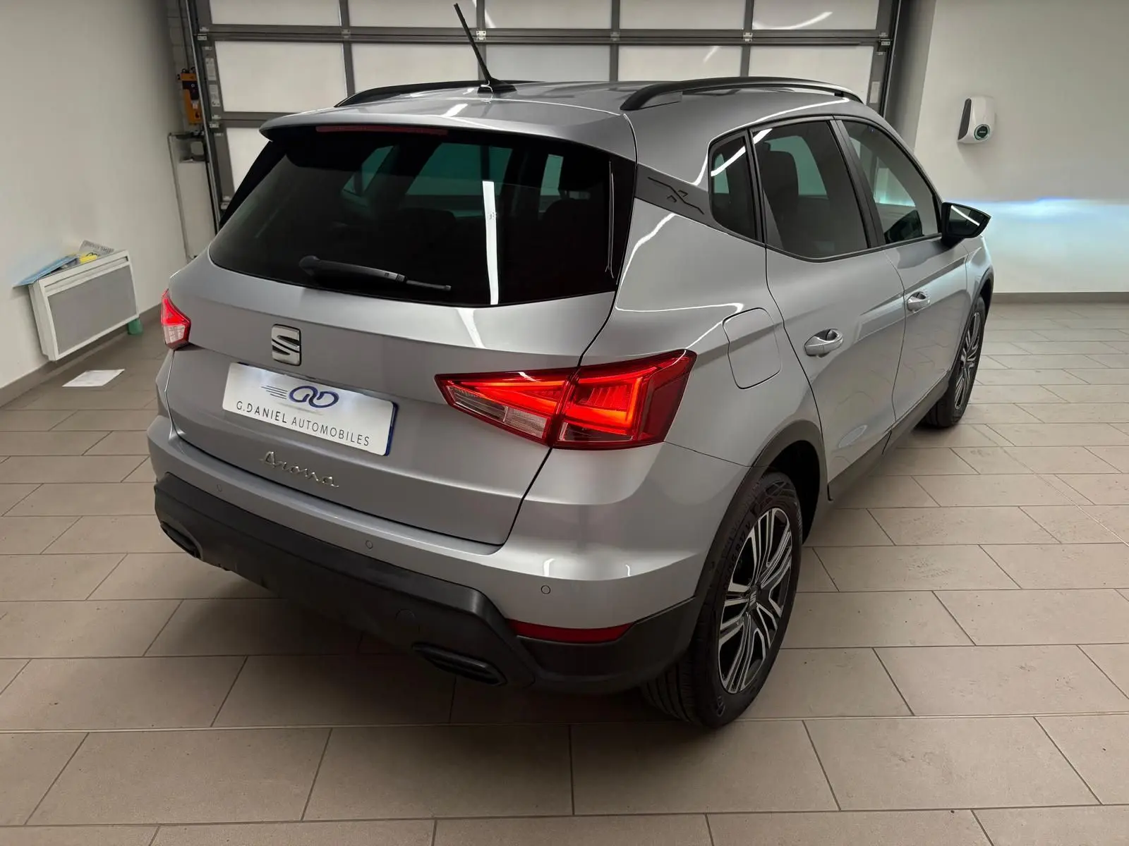 SEAT Arona gris urbain en 3/4 arrière droit, vitres arrière surteintées et feux arrière allumés en intérieur.