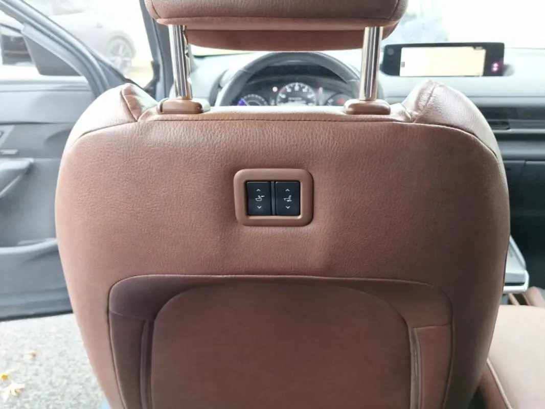 Vue intérieure arrière du siège conducteur en cuir marron avec commandes électriques, tableau de bord et volant visibles dans une Mazda MX-30 gris 2021.
