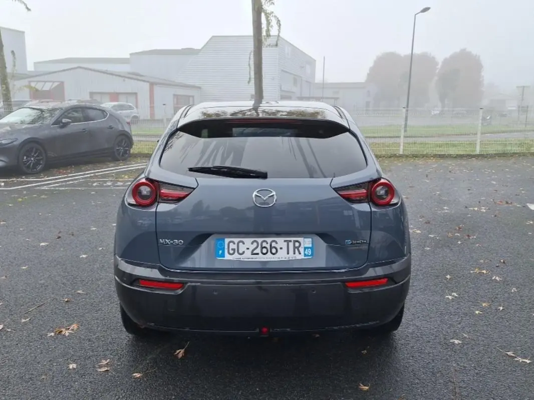 Vue arrière d'une Mazda MX-30 gris électrique 2021 avec feux ronds caractéristiques et plaque d'immatriculation française.
