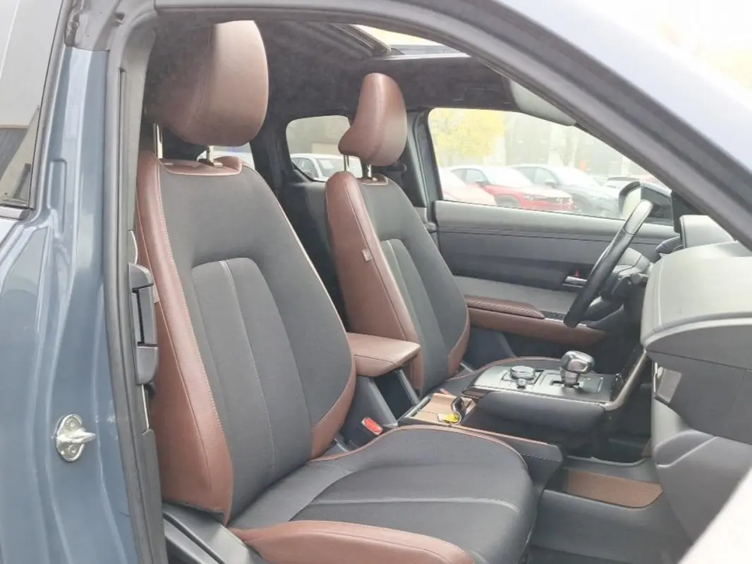 Vue intérieure côté conducteur du Mazda MX-30 gris 2021, sièges bi-matière marron et noir avec console centrale moderne.