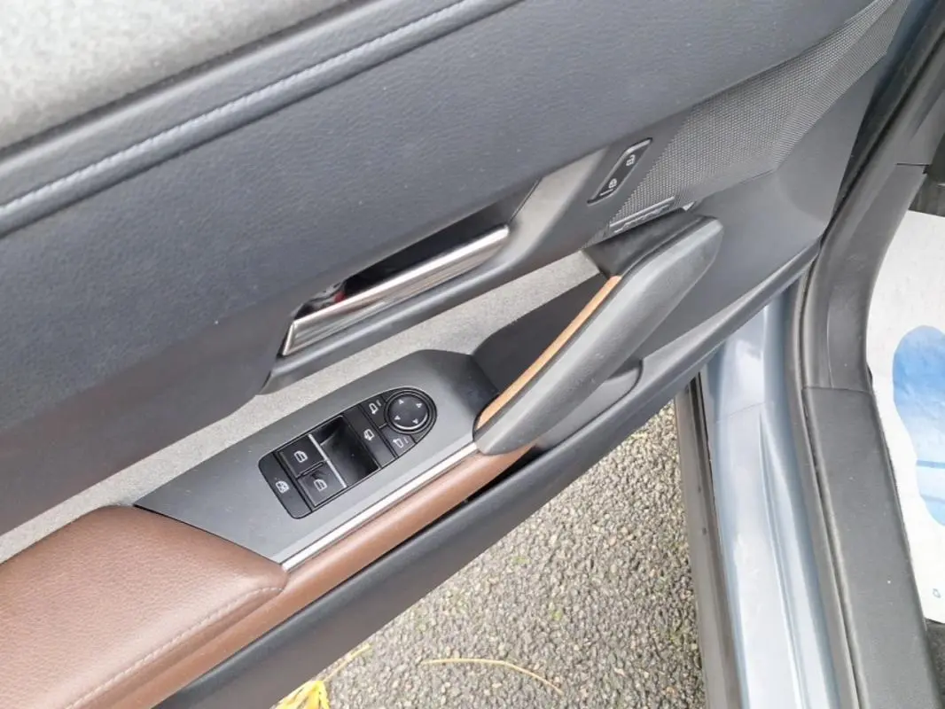 Détail de la porte avant gauche gris clair du Mazda MX-30 2021 avec commandes de vitres et insert marron.