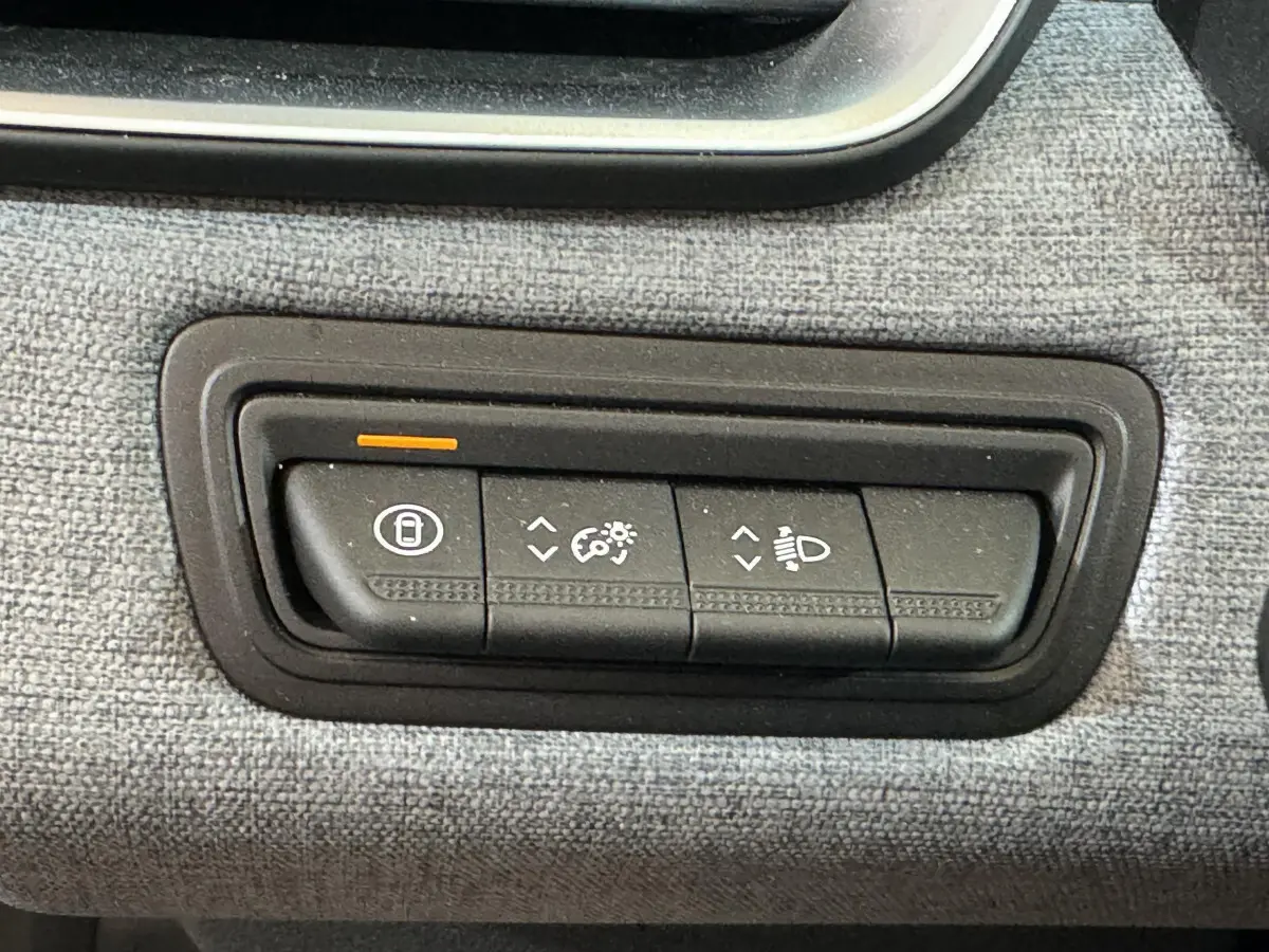 Gros plan sur les commandes d’éclairage et de verrouillage sur tableau de bord gris clair d’une Renault Clio Evolution 2025.