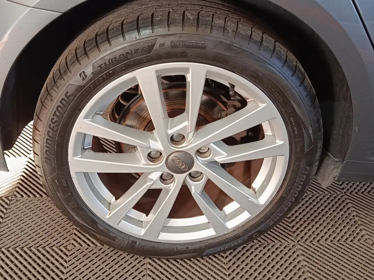 Gros plan sur la roue avant droite d'une Audi A3 gris foncé, avec jante alliage argentée et pneu Bridgestone.