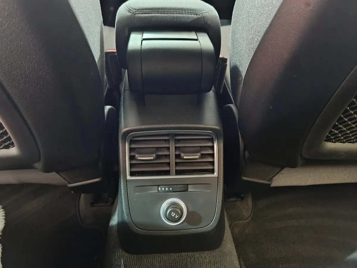 Vue rapprochée de la console centrale arrière noire avec bouches d’aération et prise 12V de l’Audi A3 gris foncé.