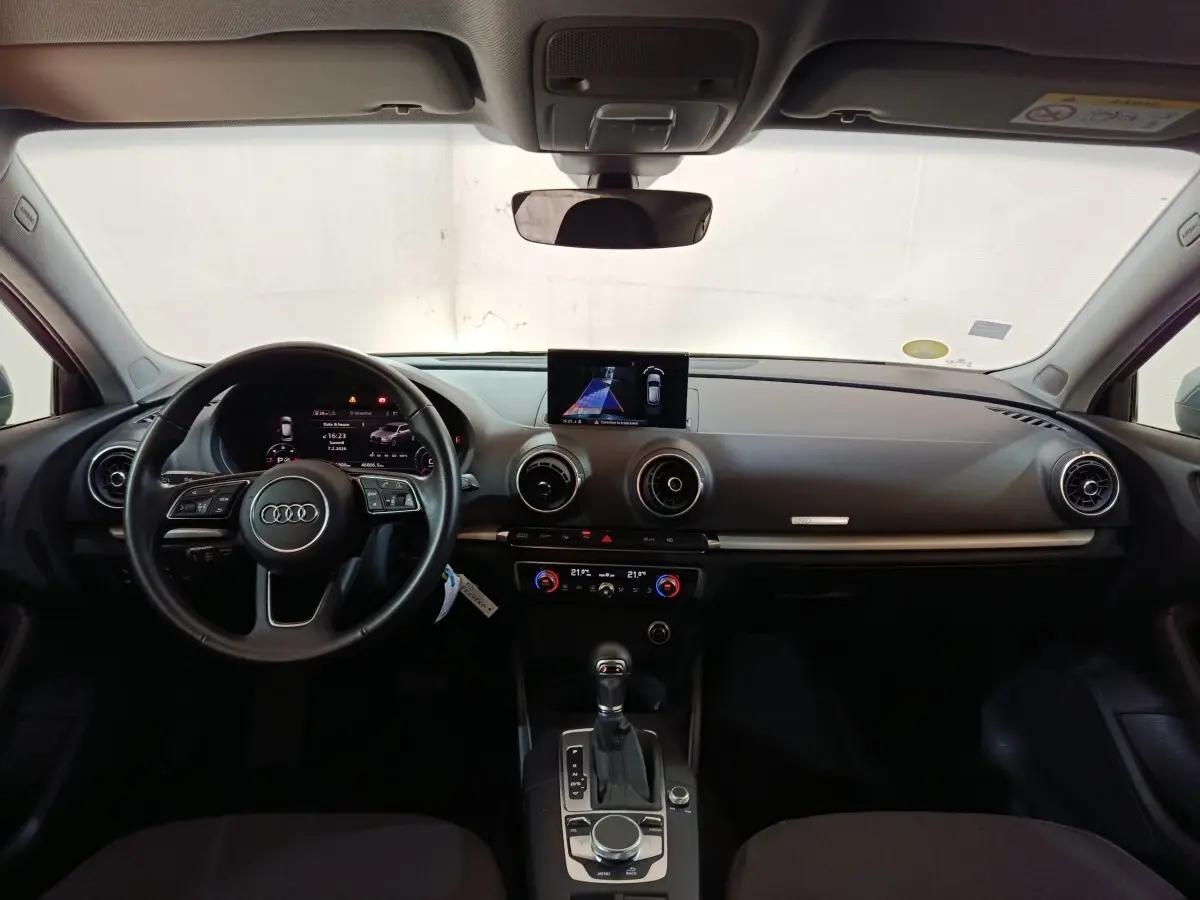 Vue intérieure frontale de l'Audi A3 35 TDI 2020 avec tableau de bord noir et écran central affichant l'aide au stationnement.