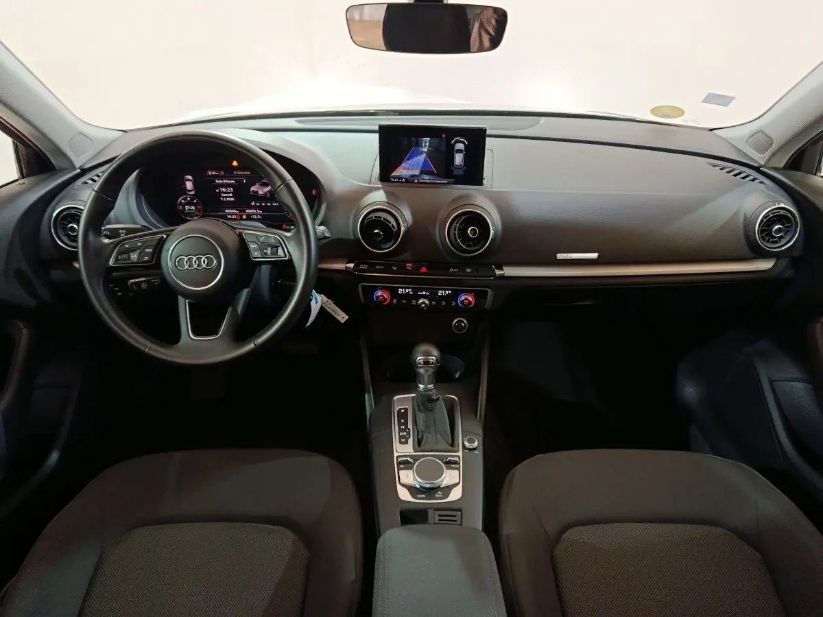 Vue intérieure de face de l'Audi A3 35 TDI Business Line 2020, tableau de bord gris avec écran central et volant cuir noir.