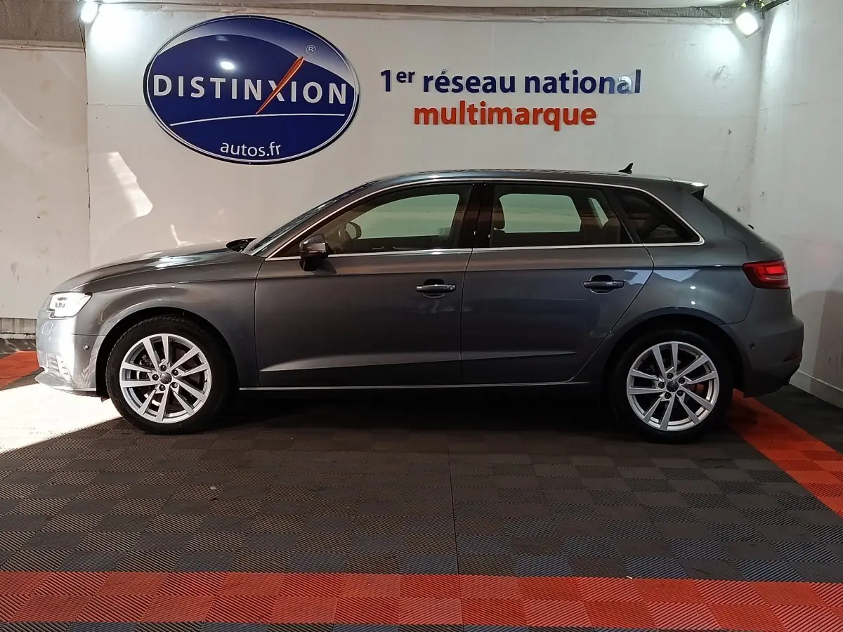 Profil latéral droit d'une Audi A3 gris foncé 2020, avec jantes alliage et feux arrière LED visibles, en intérieur showroom.
