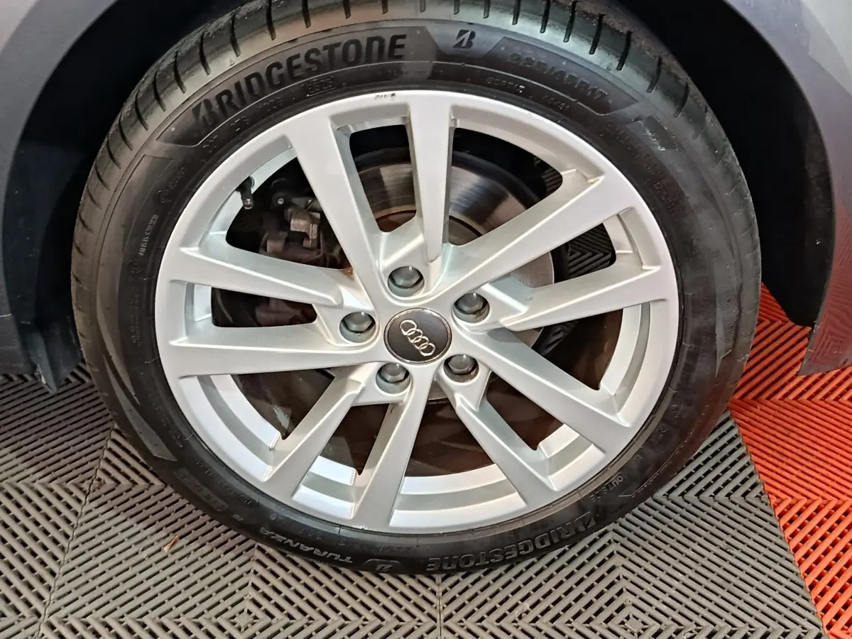 Gros plan sur la roue avant droite d'une Audi A3 gris foncé, jante alliage à 10 branches et pneu Bridgestone.