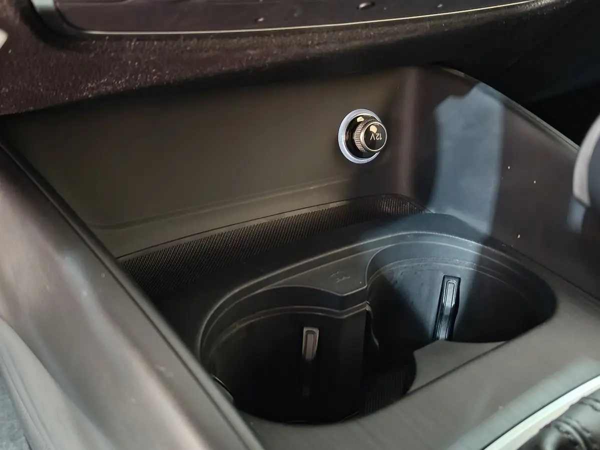 Vue rapprochée de la console centrale noire de l’Audi A3 35 TDI avec prise 12V et porte-gobelets intégrés.