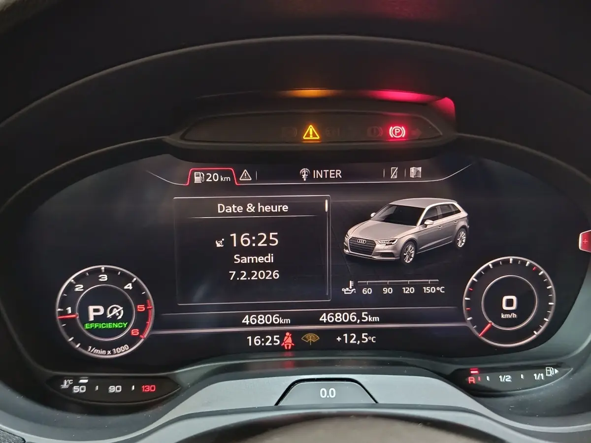 Vue rapprochée du tableau de bord numérique d’une Audi A3 gris foncé, affichant date, heure et indicateurs de conduite.