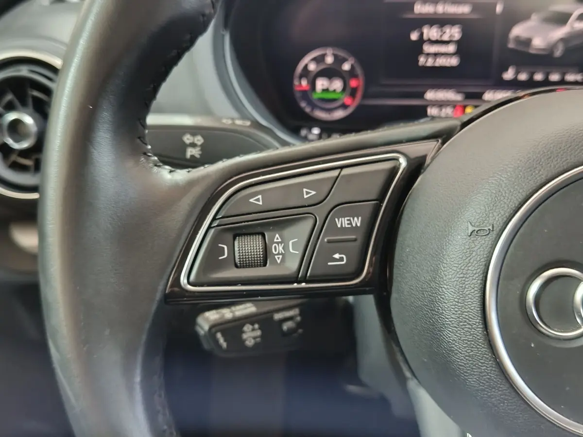 Gros plan sur le volant cuir noir de l'Audi A3 35 TDI 2020 avec commandes multifonctions côté gauche et tableau de bord numérique.
