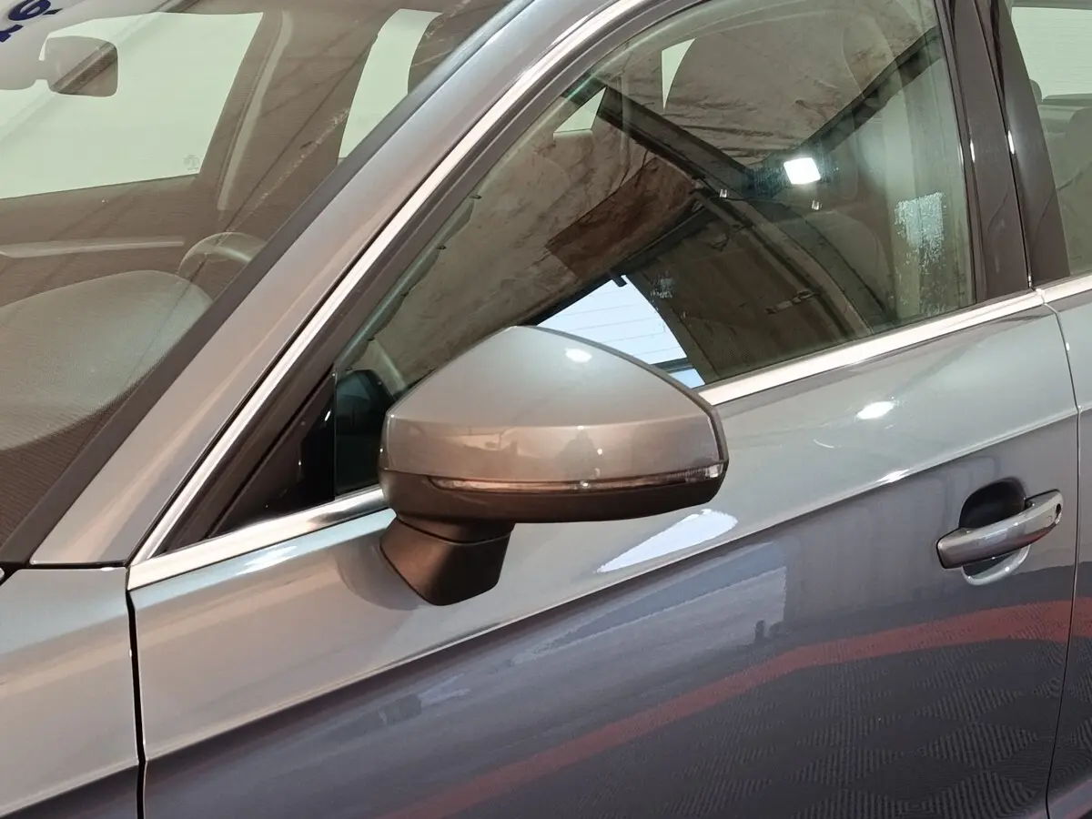 Vue rapprochée du rétroviseur côté conducteur d'une Audi A3 gris foncé, avec poignée de porte visible.
