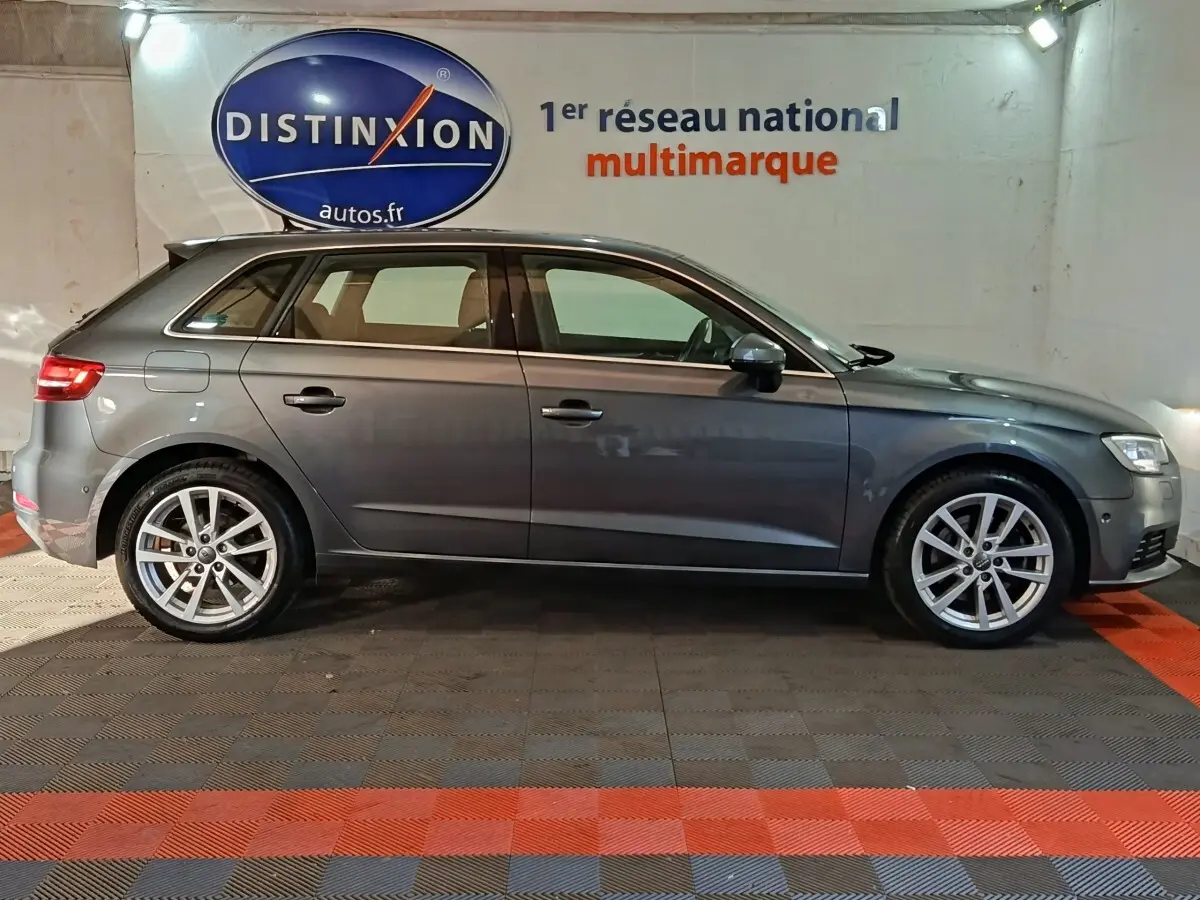 Profil côté droit d'une Audi A3 gris foncé 2020, avec jantes alliage et feux arrière LED visibles, en intérieur showroom.