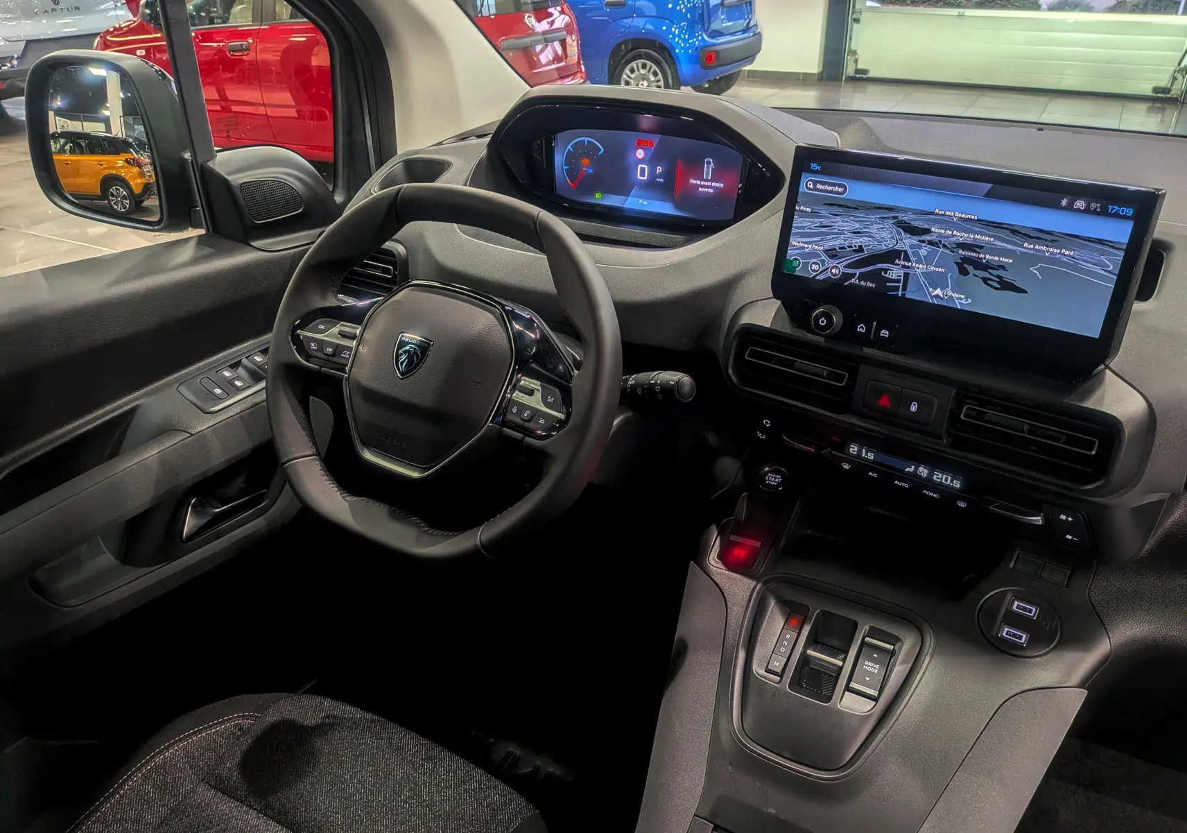 Vue intérieure côté conducteur du Peugeot Rifter 2025 gris acier, avec tableau de bord numérique et écran tactile central affichant la navigation.