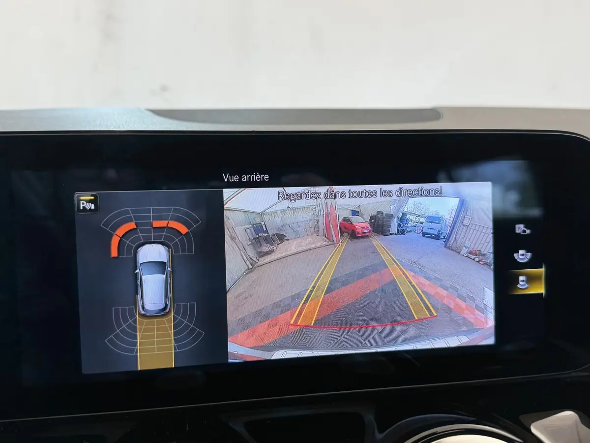 Affichage écran multimédia montrant la caméra de recul et l'aide au stationnement du Mercedes GLA 250 e gris clair.