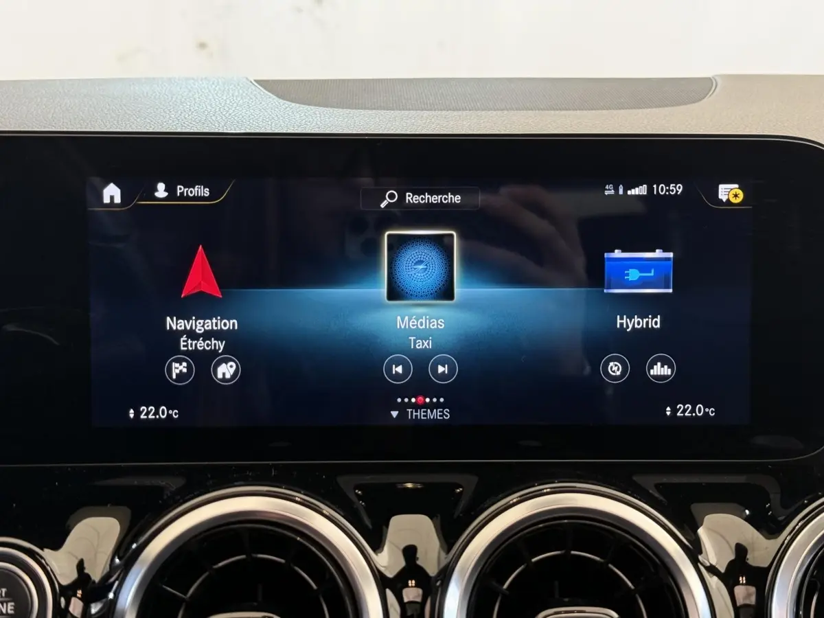 Vue rapprochée de l’écran tactile central et des aérateurs ronds chromés du tableau de bord d’une Mercedes GLA 250 e AMG Line gris clair.