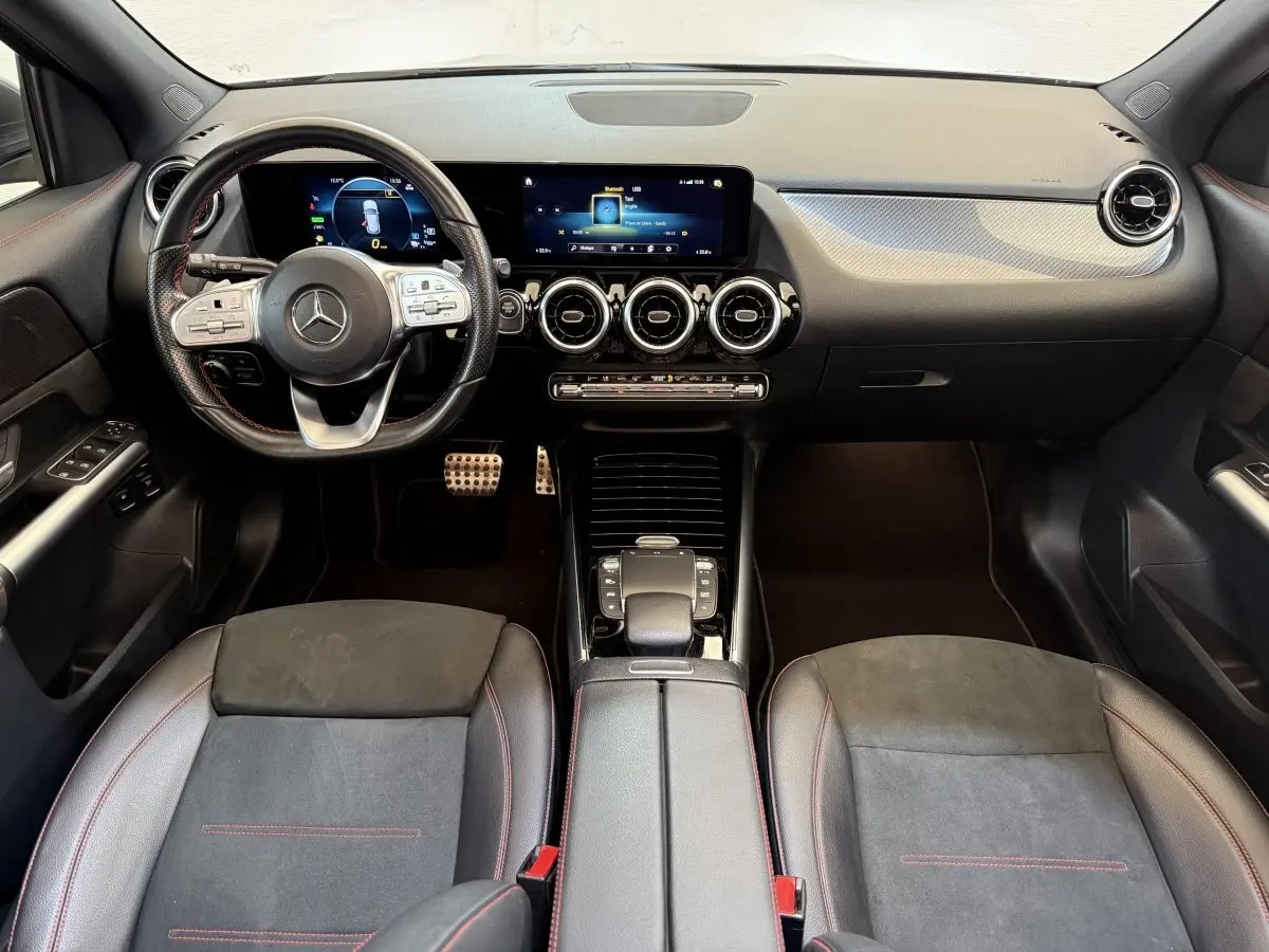 Vue intérieure avant de la Mercedes GLA 250 e AMG Line 2023, tableau de bord noir avec écran tactile et volant cuir.
