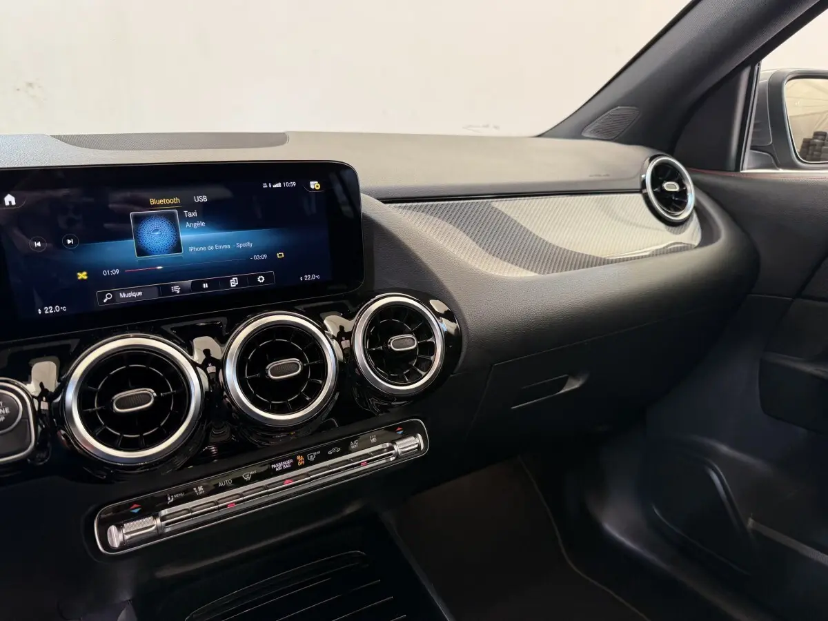 Vue intérieure côté passager du tableau de bord noir et gris clair avec écran tactile et aérateurs ronds Mercedes GLA 250 e AMG Line 2023.
