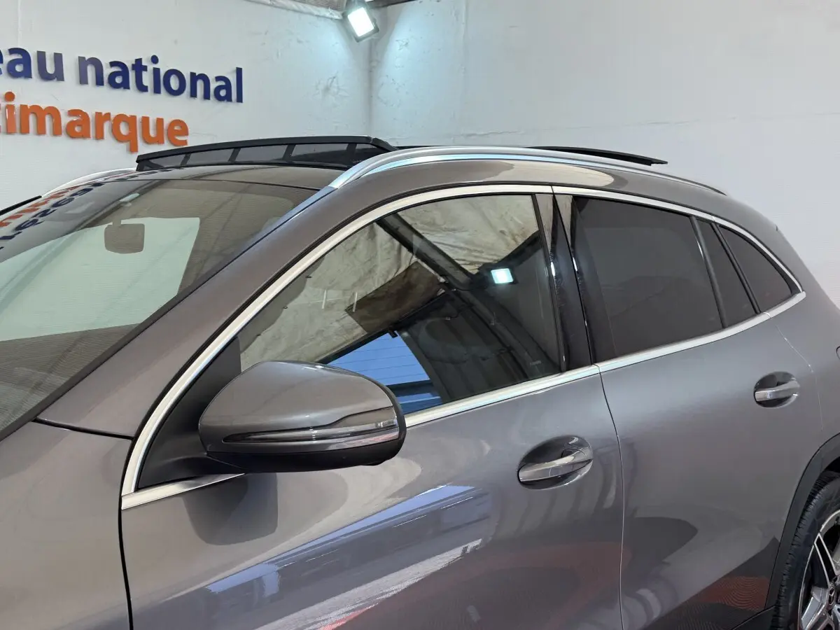Vue latérale gauche d'un Mercedes GLA 250 e AMG Line gris clair avec rétroviseur et vitres teintées.