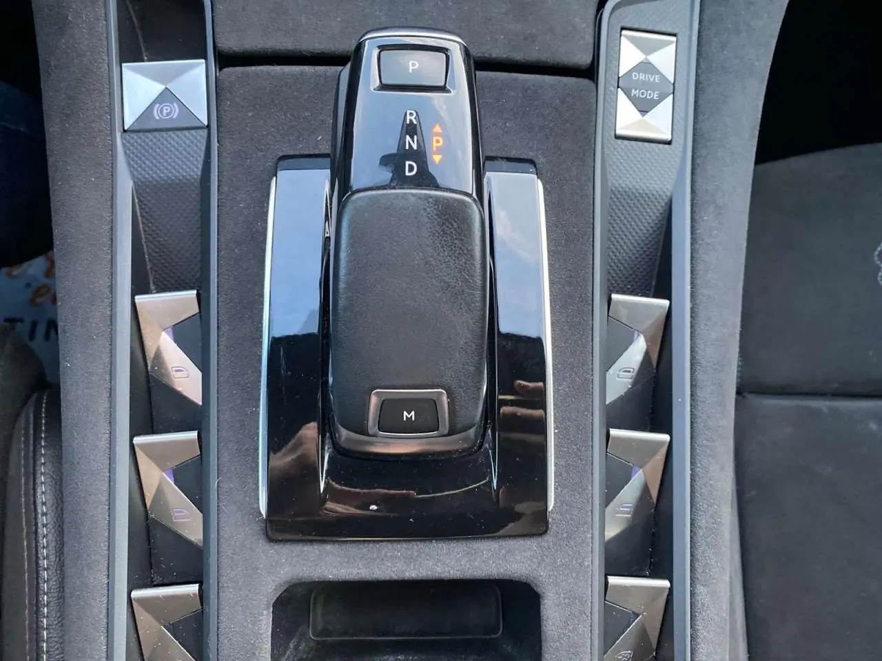 Vue rapprochée de la console centrale noire du DS7 Crossback gris foncé, avec levier de vitesses automatique et boutons triangulaires.