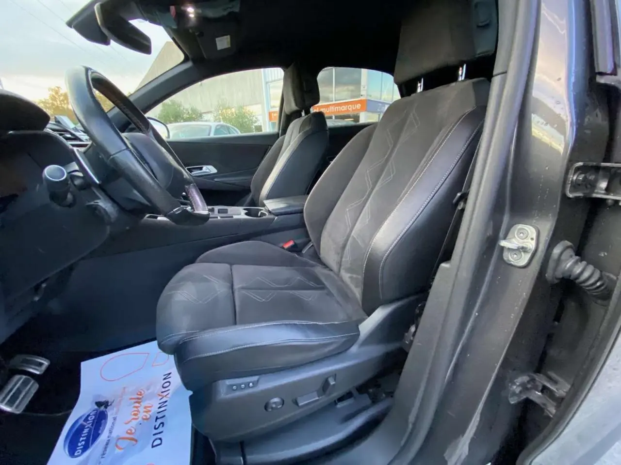 Vue intérieure côté conducteur du DS7 Crossback gris foncé, mettant en valeur les sièges en cuir avec surpiqûres décoratives.