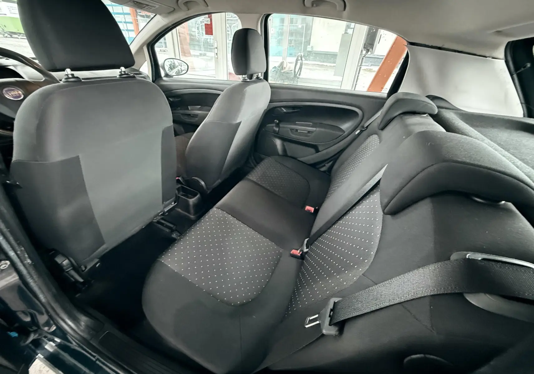 Vue intérieure arrière montrant les sièges arrière noirs à motifs gris de la Fiat Punto 1.2 i 65 de 2009.