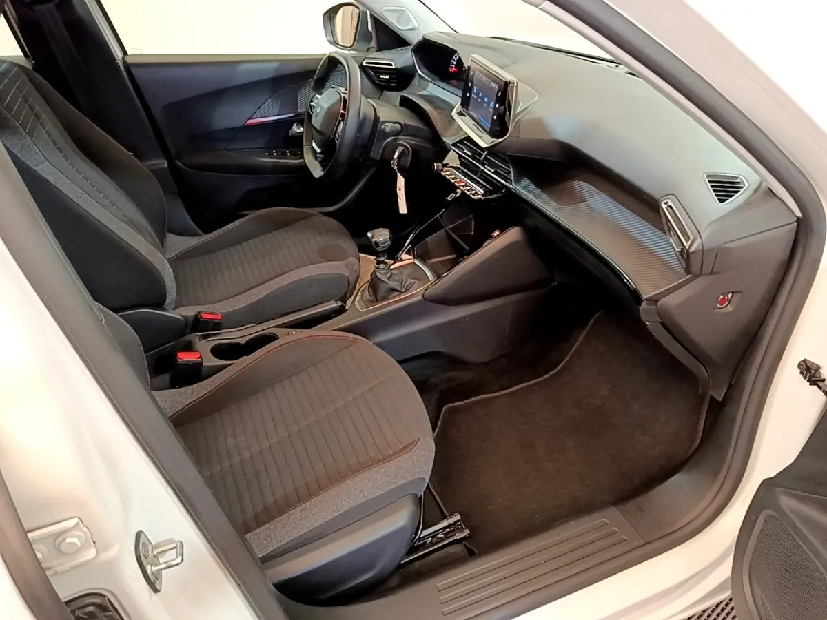 Intérieur avant droit du Peugeot 2008 blanc 2021, montrant sièges tissu, volant cuir et écran tactile central.