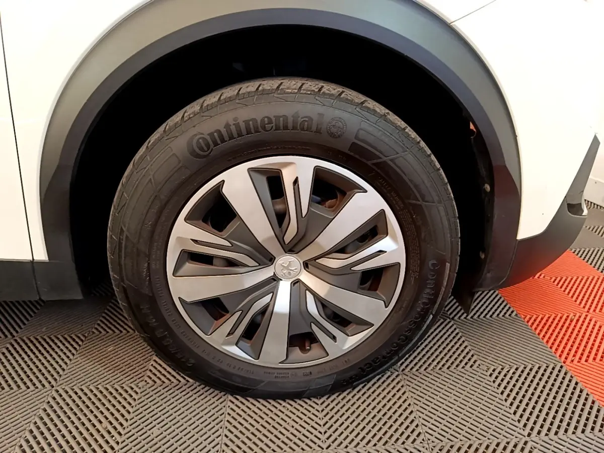 Gros plan sur la roue avant droite d’un Peugeot 2008 blanc, avec jante alliage et pneu Continental visible.