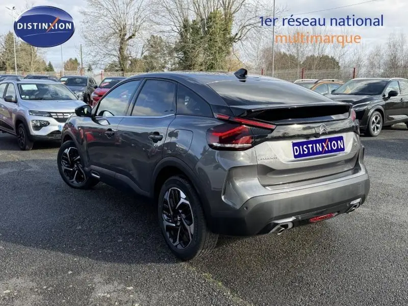 Vue 3/4 arrière droite d'une Citroën C4 gris 2024 avec feux arrière LED et jantes noires distinctives.