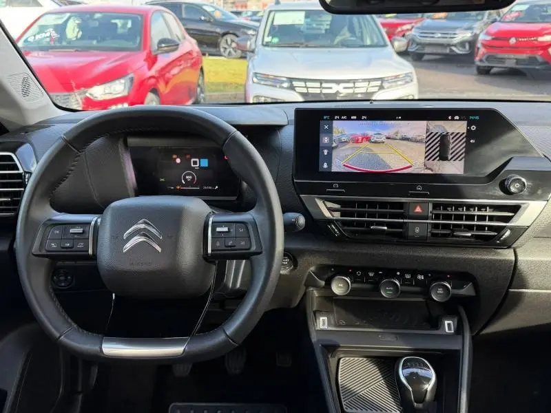 Vue intérieure du poste de conduite du Citroën C4 gris 2024, avec volant multifonction et écran tactile affichant la caméra de recul.