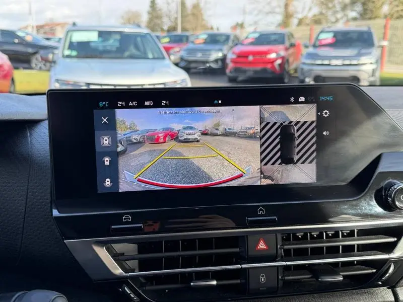 Écran central d’une Citroën C4 2024 montrant la caméra de recul avec vue arrière et vue aérienne du véhicule gris.