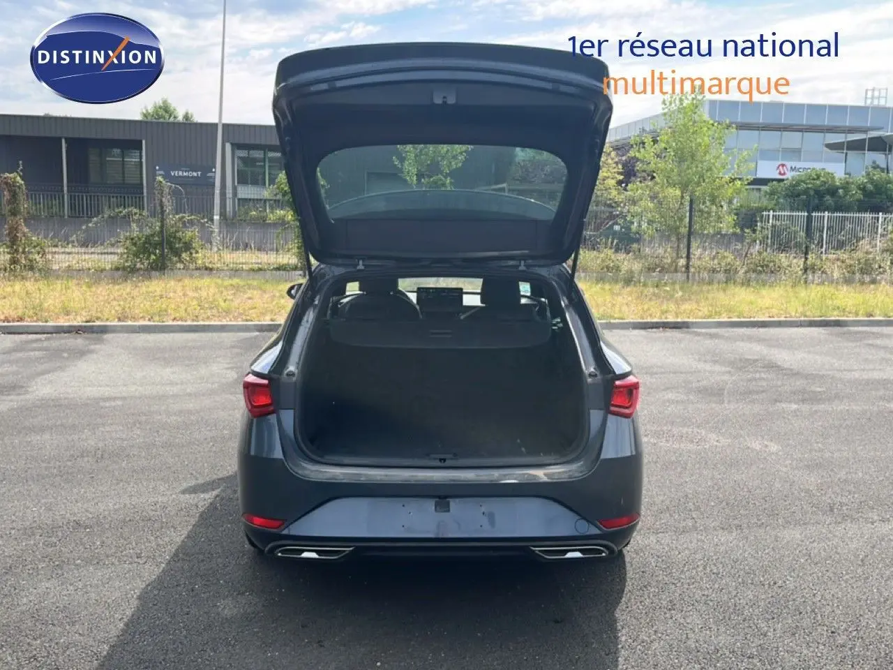 Vue arrière d'une SEAT LEON ST gris magnétique métal 2025 avec coffre ouvert sur un parking extérieur.