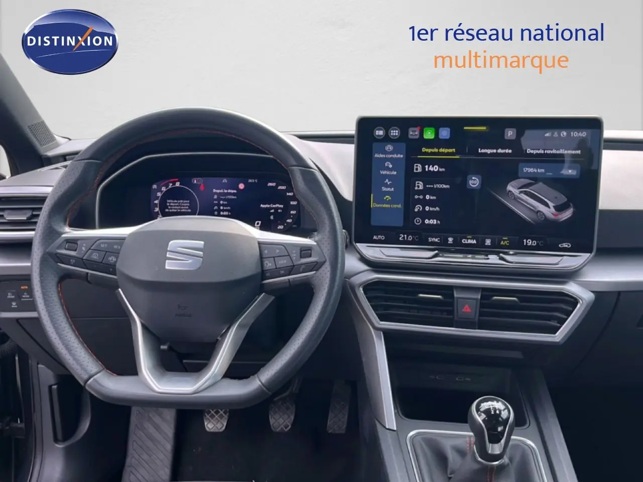 Vue intérieure centrée sur le volant et la console centrale d'une SEAT LEON ST gris magnétique, avec écran tactile et boîte manuelle.