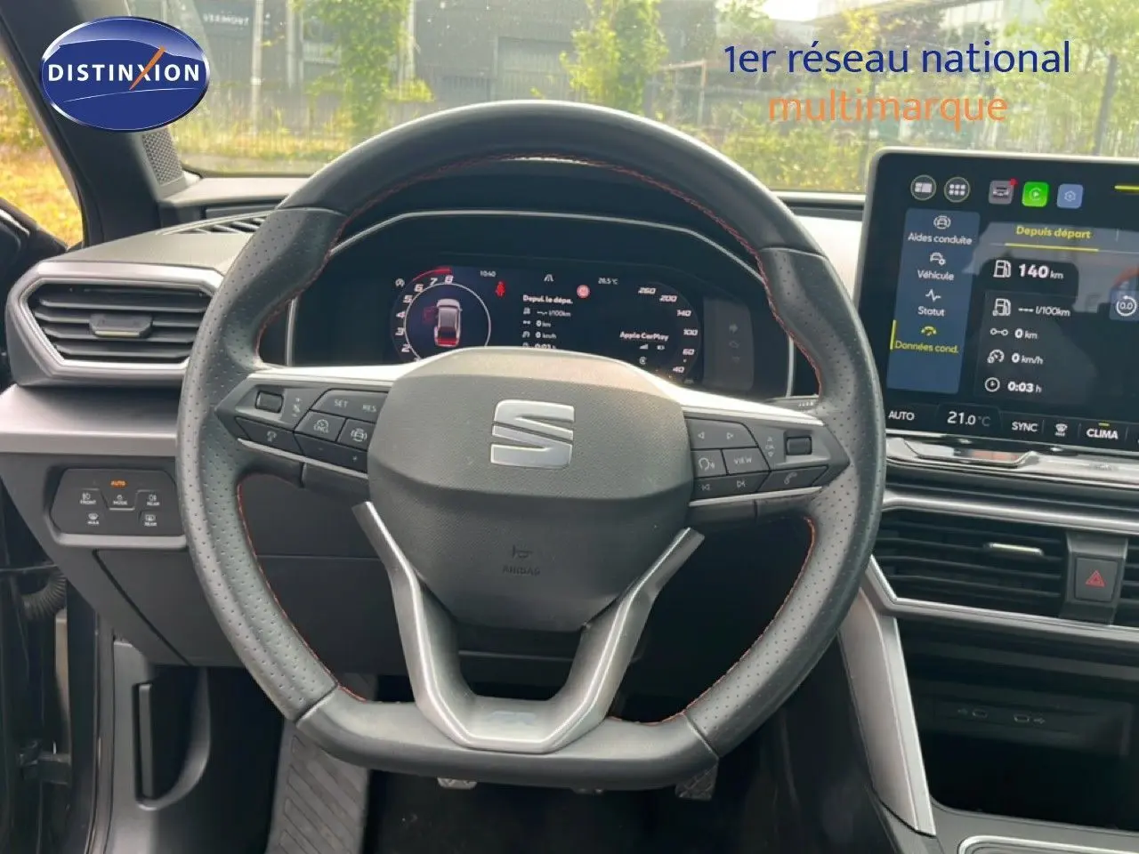 Vue intérieure centrée sur le volant perforé et les écrans numériques du tableau de bord d’une SEAT Leon ST 2025.