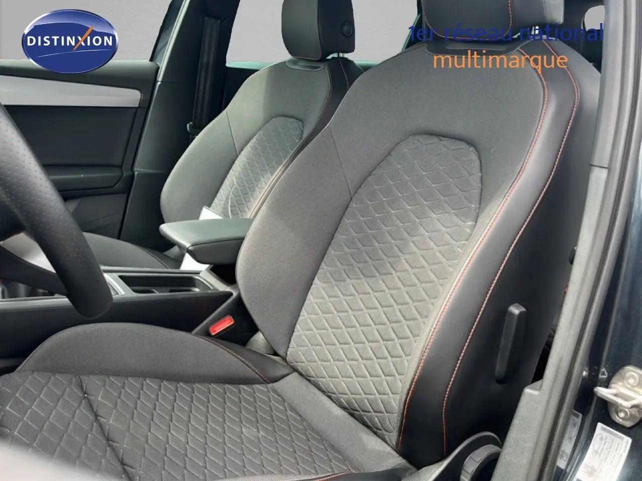 Gros plan sur les sièges avant gris noir avec surpiqûres orange du SEAT LEON ST 2025, vue côté gauche intérieur conducteur.