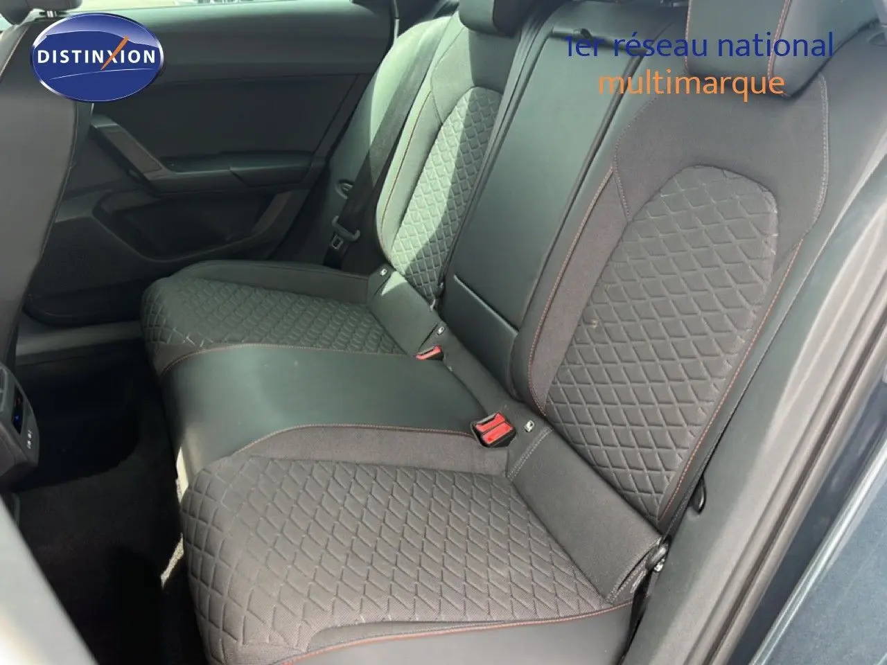 Vue intérieure des sièges arrière en tissu gris noir avec surpiqûres rouges d'une SEAT LEON ST 2025, porte ouverte côté droit.