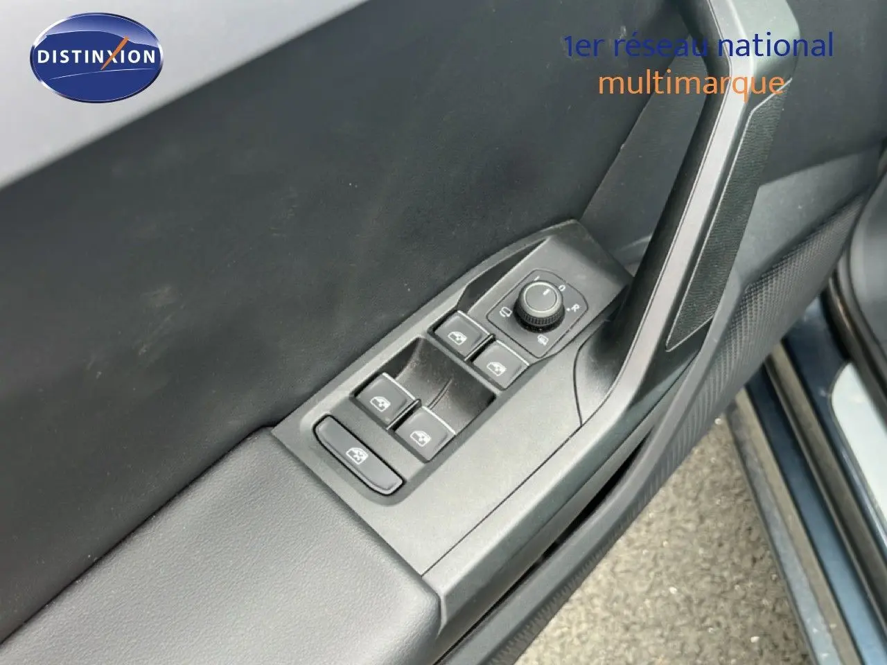Vue rapprochée des commandes de lève-vitres et rétroviseurs sur la porte côté conducteur d’une SEAT LEON ST gris magnétique.